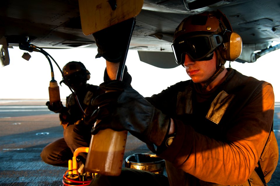 US Navy 111017-N-BT887-525 Aviation Structural Mechanic Airman Marcus Martinez takes an oil sample from an F-A-18C Hornet assigned to the Golden Dr