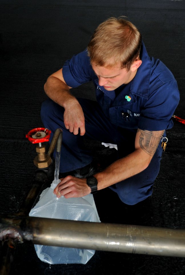 US Navy 111019-N-SF704-117 Hull Maintenance Technician Fireman Joshua Fayette, from Newton, Kan., fills a carton with water with a potable water ri