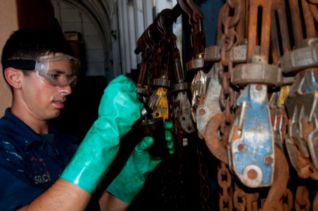 US Navy 111019-N-ER662-148 Aviation Boatswain's Mate (Handler) Airman Surge Soucy oils chains in the hangar bay of the forward deployed amphibious