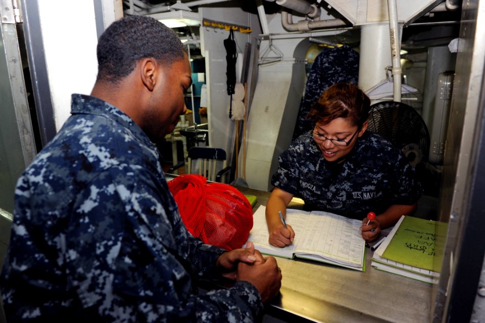 US Navy 111020-N-AU622-048 Aviation Boatswain's Mate (Handling) Airman Betzaida Mendoza assists a Sailor in the laundry customer service window