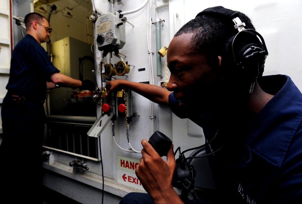 US Navy 111018-N-XE109-009 Electrician's Mate Fireman Samuel D. Jenkins, right, communicates to storeroom personnel while Hull Technician 3rd Class