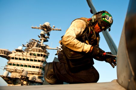 US Navy 111017-N-BT887-504 Aviation Electronics Technician 3rd Class Matthew Cardenas removes a door fastener from an F-A-18C Hornet assigned to th