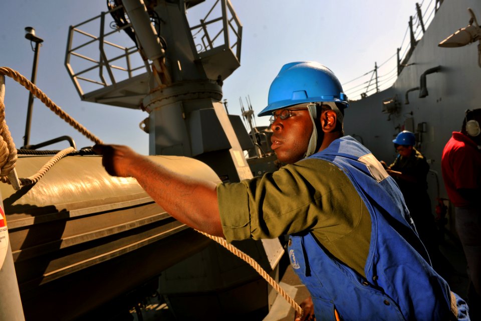 US Navy 111019-N-YZ751-047 Boatswain's Mate 3rd Class Carl-Evans Augustin prepares to lower a rigid-hull inflatable boat into the water