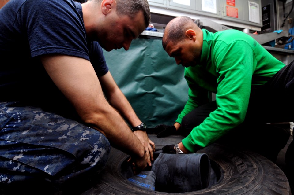US Navy 111021-N-JD217-013 Sailors insert a tube into a tractor tire aboard the aircraft carrier USS George H.W. Bush (CVN 77)