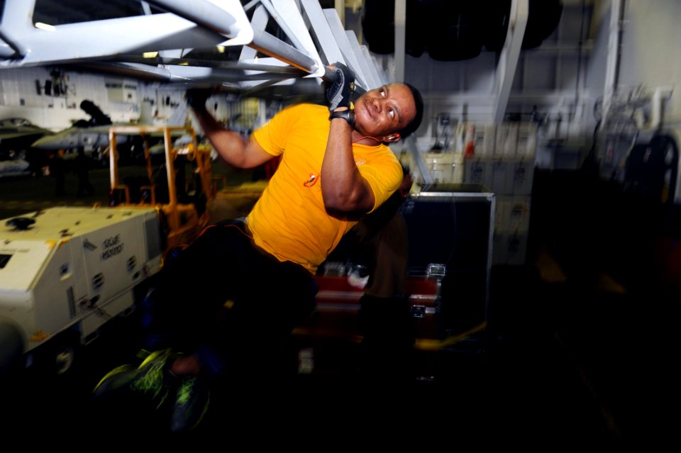 US Navy 111019-N-AU622-033 Mass Communication Specialist Seaman Justin Wesley performs pull-ups on TRX bars in the hangar bay of the aircraft carri