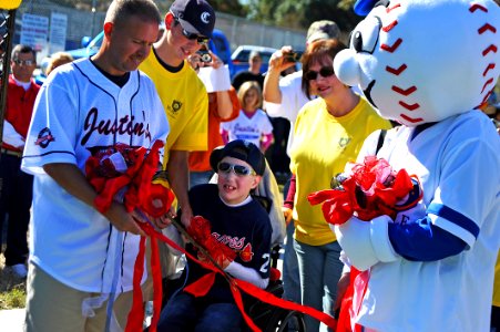US Navy 111022-N-YR391-024 Senior Chief Missile Technician Jeff Norris and the Miracle League mascot hold a ribbon for a child to cut and officiall