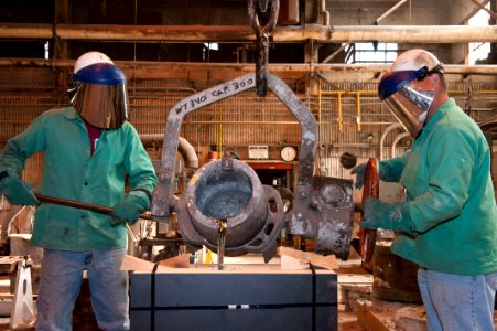 US Navy 111021-N-ZZ999-001 Shipbuilders Jason West, left, and Kevin Forrest pour molten pewter into a mold for production of the Quicken Loans Carr photo