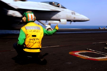 US Navy 111024-N-OY799-217 Aviation Boatswain's Mate (Equipment) 2nd Class Brandon Fulton signals for launching of an F-A-18E Super Hornet