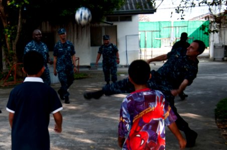 US Navy 111022-N-EA192-068 Sailors assigned to the guided-missile destroyer USS Mustin (DDG 89) play soccer with children during a community servic photo