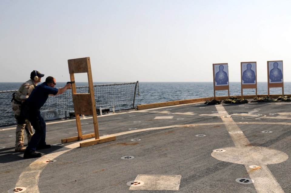 US Navy 111024-N-XQ375-344 Information Systems Technician 3rd Class Clint Huffman fires a 9mm pistol during a weapons qualification aboard the guid