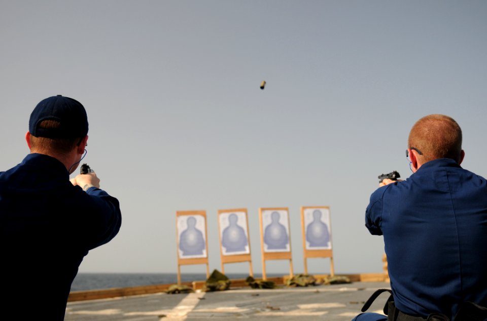 US Navy 111022-N-XQ375-547 Operations Specialist 3rd Class Dustin Reeves, left, and Lt. j.g. Jason Coyle fire 9mm pistols during a weapons qualific