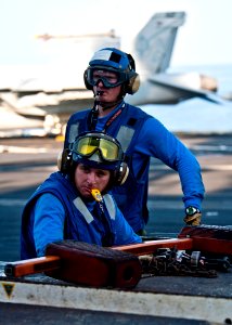 US Navy 111025-N-BT887-129 Aviation Boatswain's Mate (Handling) Airman Adam Insley maneuvers an MH-60S Sea Hawk helicopter assigned to the Eightbal
