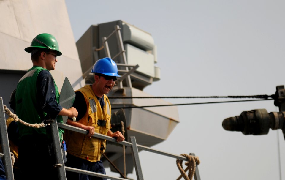 US Navy 111023-N-XQ375-272 Boatswain's Mate Seaman Cameron Rodgers, left, signals to the Military Sealift Command fleet replenishment oiler USNS Le