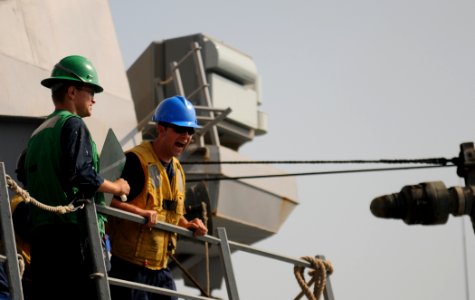 US Navy 111023-N-XQ375-272 Boatswain's Mate Seaman Cameron Rodgers, left, signals to the Military Sealift Command fleet replenishment oiler USNS Le