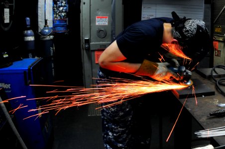 US Navy 111025-N-JH293-061 Hull Maintenance Technician 3rd Class Michael Evans grinds a weld aboard the submarine tender USS Emory S. Land (AS 39)