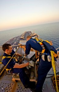 US Navy 111026-N-GC412-154 Interior Communications Electrician Firemen Brian Guilliams, left, and Thomas Trevillyan lower the ship's whistle from t