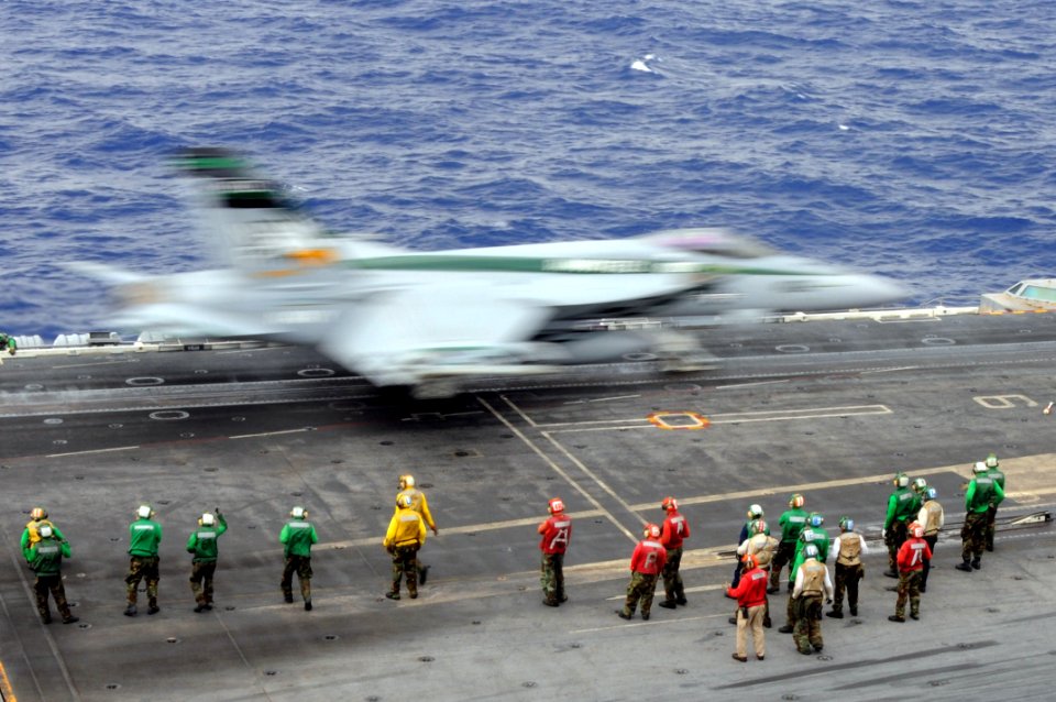 US Navy 111025-N-JO245-033 An F-A 18E Super Hornet assigned to the Dambusters of Strike Fighter Squadron (VFA) 195 launches as Sailors stand by on