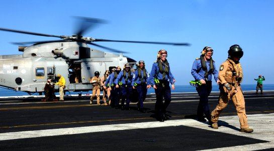 US Navy 111024-N-OY799-379 British Sailors are escorted off an EH-101 Merlin helicopter assigned to the Royal Navy frigate HMS St. Albans (F 83) ab