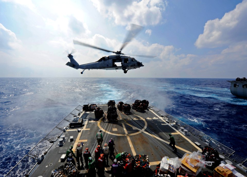 US Navy 111025-N-VH839-048 An MH-60R Sea Hawk helicopter transfers supplies to the flight deck of the Arleigh Burke-class guided-missile destroyer