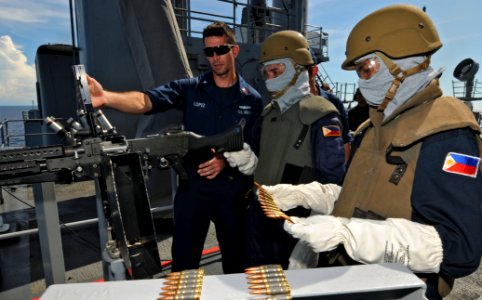 US Navy 111025-N-MW330-811 Fire Controlman 2nd Class Peter Lopez explains how to reload an M240B machine gun