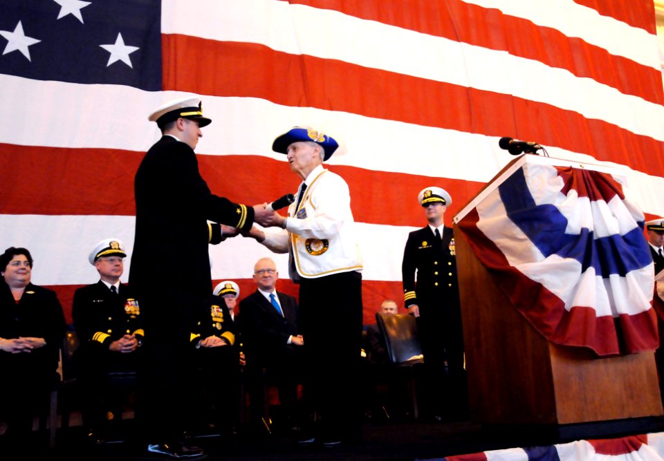 US Navy 111029-N-FC670-232 World War II submarine veteran Joe Cox, right, passes the long glass to set the first watch during the commissioning cer