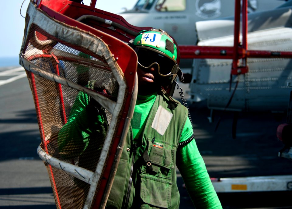 US Navy 111026-N-BT887-087 Aviation Machinist's Mate 3rd Class Olamide Osude carries a turn screen across the flight deck aboard the Nimitz-class a