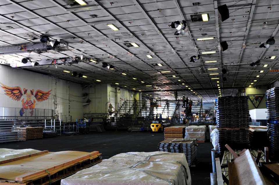 US Navy 111108-N-ZI635-177 Civilian contractors erect bleachers as workers construct an alternate basketball arena in the hangar bay aboard Nimitz
