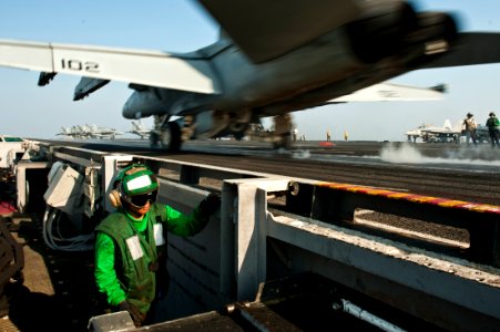 US Navy 111027-N-BT887-490 Aviation Boatswain's Mate (Equipment) Airman Mary Jane Crews runs to collect a hold-back bar as an F-A-18F Super Hornet