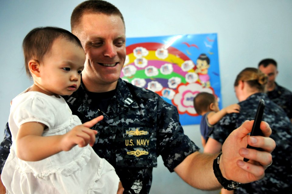 US Navy 111025-N-WW409-387 Lt. John Lundgren, assigned to the guided-missile destroyer USS Mustin (DDG 89), plays with a child at the Pattaya Orpha