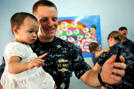 US Navy 111025-N-WW409-387 Lt. John Lundgren, assigned to the guided-missile destroyer USS Mustin (DDG 89), plays with a child at the Pattaya Orpha photo