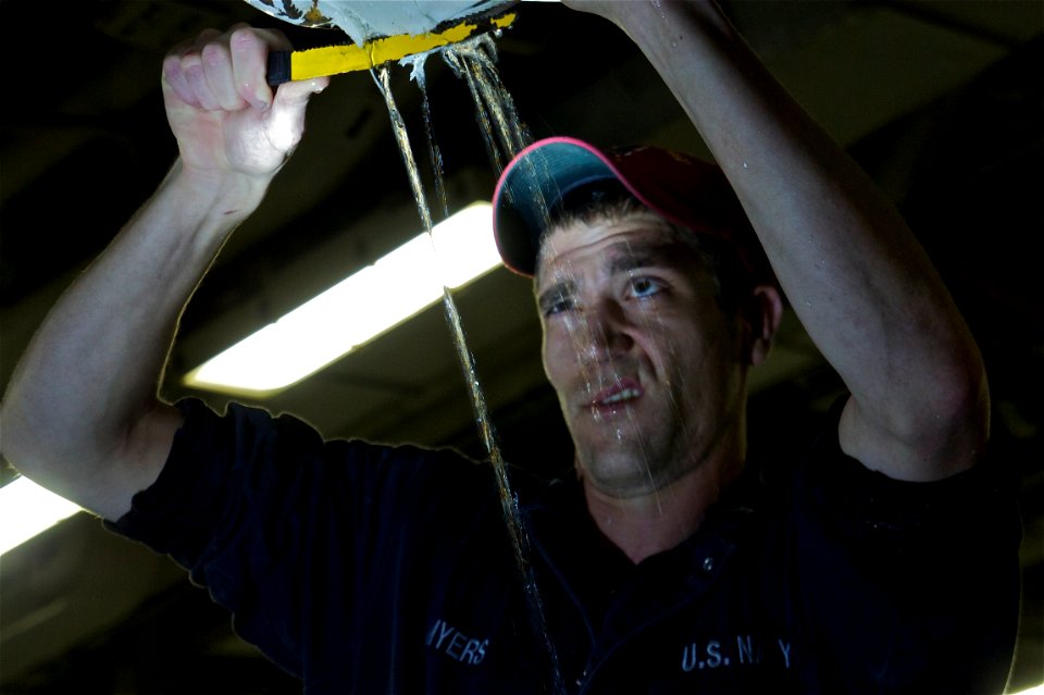 US Navy 111027-N-ZC343-745 Hull Technician 2nd Class John Myers removes the lagging from a ruptured pipe in the upper vehicle storage deck
