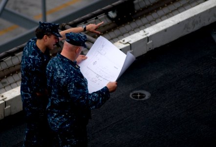 US Navy 111101-N-TZ605-057 Sailors review plans as construction begins on the basketball court for the Quicken Loans Carrier Classic