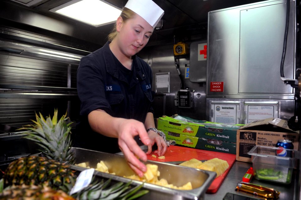 US Navy 111029-N-IO627-033 Damage Controlman Fireman Nicole Hicks dices pineapple in the galley of the Arleigh Burke-class guided-missile destroyer