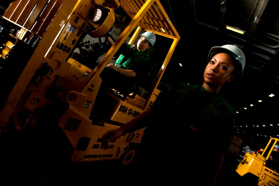 US Navy 111027-N-VN693-350 Logistics Specialist Seaman Tomiya Norris directs a forklift driver during a replenishment at sea aboard the Nimitz-clas