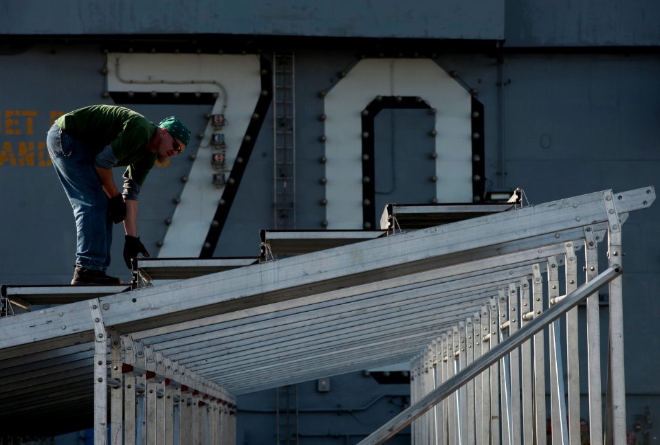 US Navy 111103-N-DR144-216 An SGA Productions stage technician assembles bleachers as workers build a basketball arena on the flight deck of the Ni