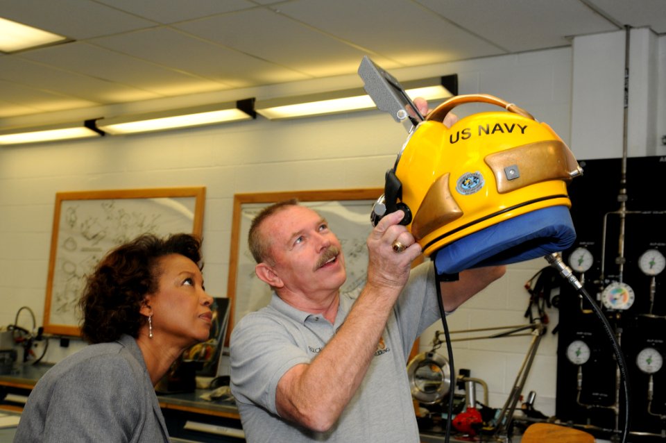 US Navy 111027-N-ZN848-072 Equipment Specialist Austin Buckman demonstrates a welding shield on a MK-21 dive helmet to Florida Lt. Gov. Jennifer Ca