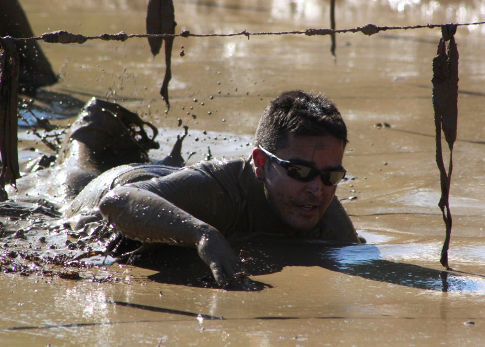 US Navy 111030-N-QF596-023 Petty Officer 1st Class Darryl Hill crawls through the mud pit, the final obstacle at the Warrior Dash in Hollister, Cal