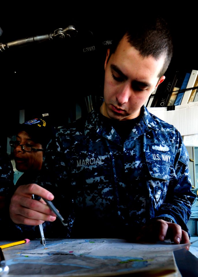 US Navy 111101-N-WJ771-018 Operations Specialist 3rd Class Chris Marcial plots a possible course for the forward-deployed amphibious dock landing s
