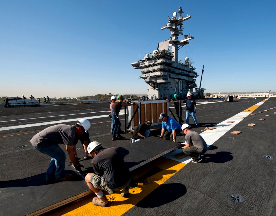 US Navy 111102-N-DR144-192 Civilian contractors lay down panels on the flight deck as workers construct a basketball arena aboard the Nimitz-class