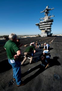US Navy 111102-N-DR144-062 Civilian contractors lay down panels on the flight deck as workers build a basketball arena aboard the Nimitz-class airc