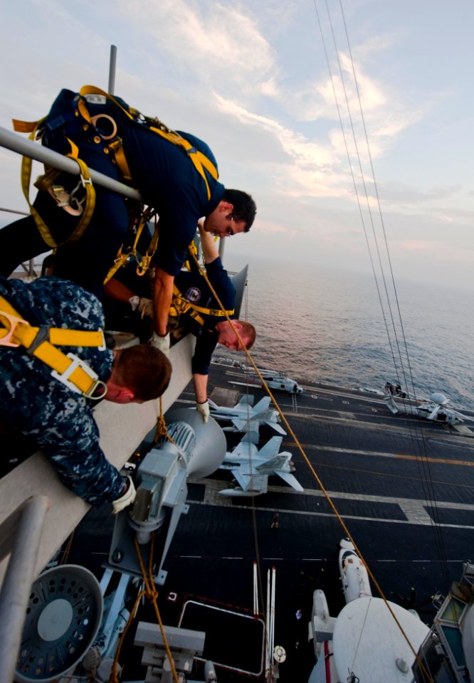 US Navy 111102-N-GC412-469 Sailors heave the ship's whistle up to the mast for installation aboard the Nimitz-class aircraft carrier USS John C. St