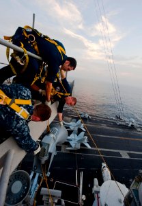 US Navy 111102-N-GC412-469 Sailors heave the ship's whistle up to the mast for installation aboard the Nimitz-class aircraft carrier USS John C. St