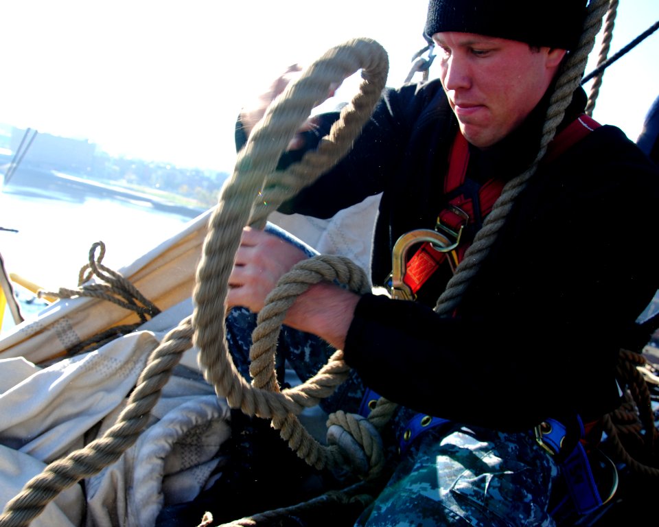 US Navy 111102-N-SH953-232 Naval Aircrewman 2nd Class Jonathan Smitherman, helps remove the main topsail from the yard of USS Constitiution for win