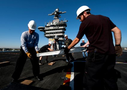 US Navy 111102-N-DR144-086 Civilian contractors lay down panels on the flight deck as workers build a basketball arena aboard the Nimitz-class airc