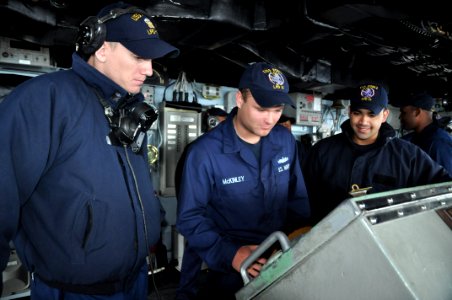 US Navy 111029-N-YX169-217 Lt. j.g. Matthew Coughlin, left, the conning officer, watches as Seaman Recruit Matthew McKinley mans the helm of the am