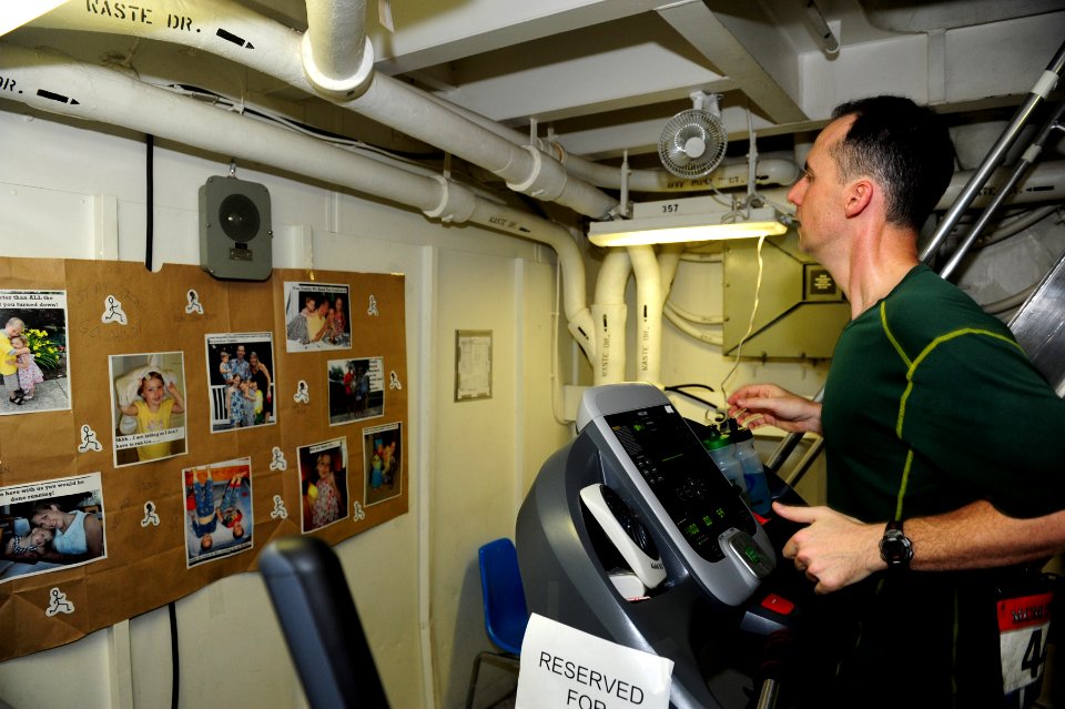 US Navy 111030-N-QL471-069 Cmdr. Joshua C. Himes looks at photos of his family while running the Marine Corps Marathon aboard the aircraft carrier
