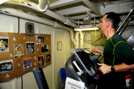 US Navy 111030-N-QL471-069 Cmdr. Joshua C. Himes looks at photos of his family while running the Marine Corps Marathon aboard the aircraft carrier