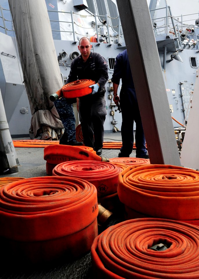 US Navy 111104-N-ED900-083 Damage Controlman 2nd Class Anthony Barrera, moves a fire hose after performing a static pressure test aboard to the Arl