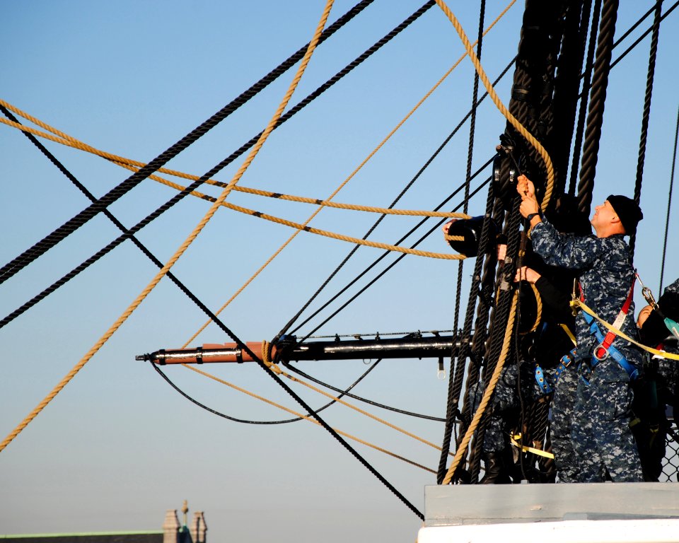 US Navy 111102-N-SH953-098 Seaman Michael Achterling ties a block to the main topsail shrouds in preparation to take the sail off USS Constitution
