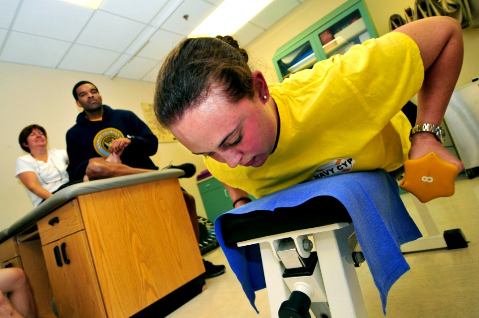 US Navy 111102-N-IZ292-050 Operations Specialist 1st Class Jennifer Funderburk, right, lifts weights during physical therapy in the Physical Therap